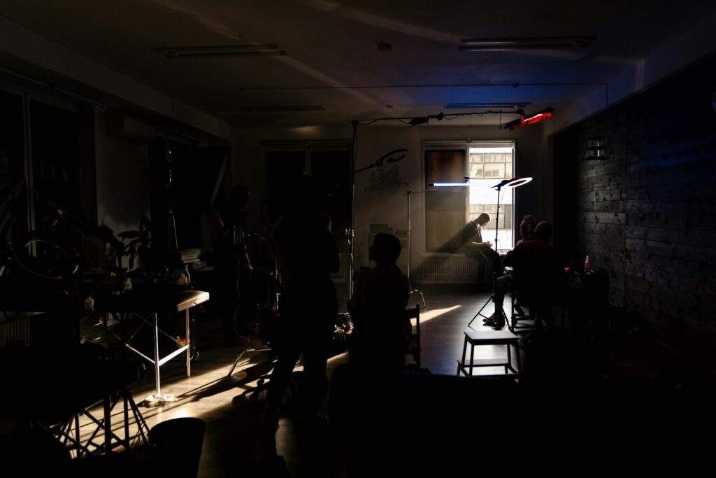 A dimly lit film set with a crew working under neon lights, creating an artistic atmosphere.